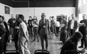 A small theatre full of people attending the Design Research Works Jamboree 2022. Dr. Joseph Lindley looking directly into the camera